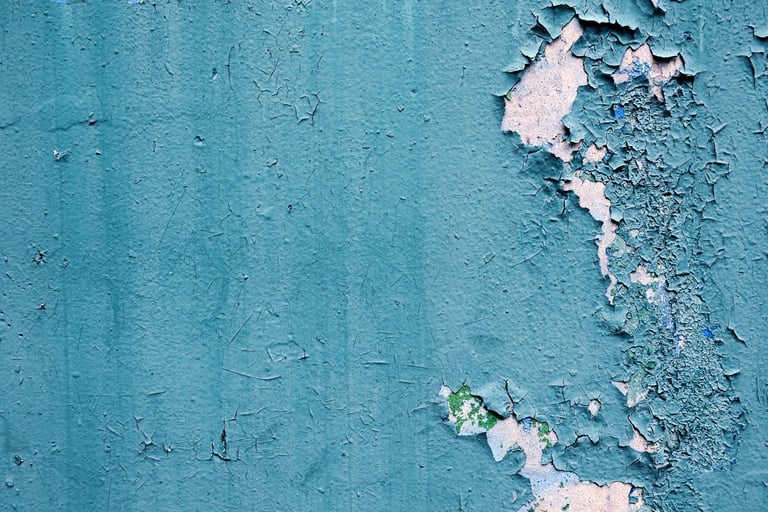 Old turquoise wall with peeling cracked paint showing traces of pressure and consequence