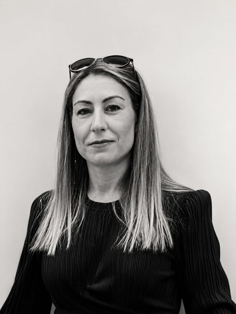 Black and white portrait of a woman with long straight hair and sunglasses on her head, wearing a dark ribbed top against a plain background