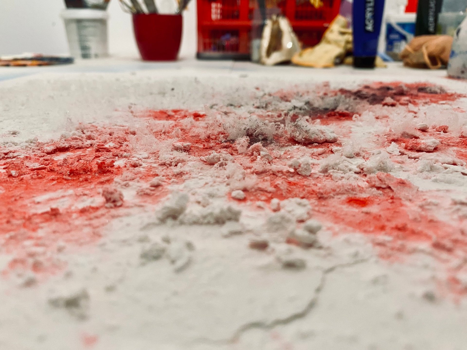 Close-up of red and gray powder scattered on a white surface — state of matter after intervention